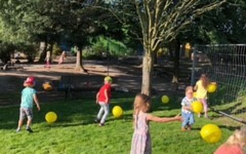 Kinder spielen auf dem frisch verlegten Rollrasen des Außengeländes.